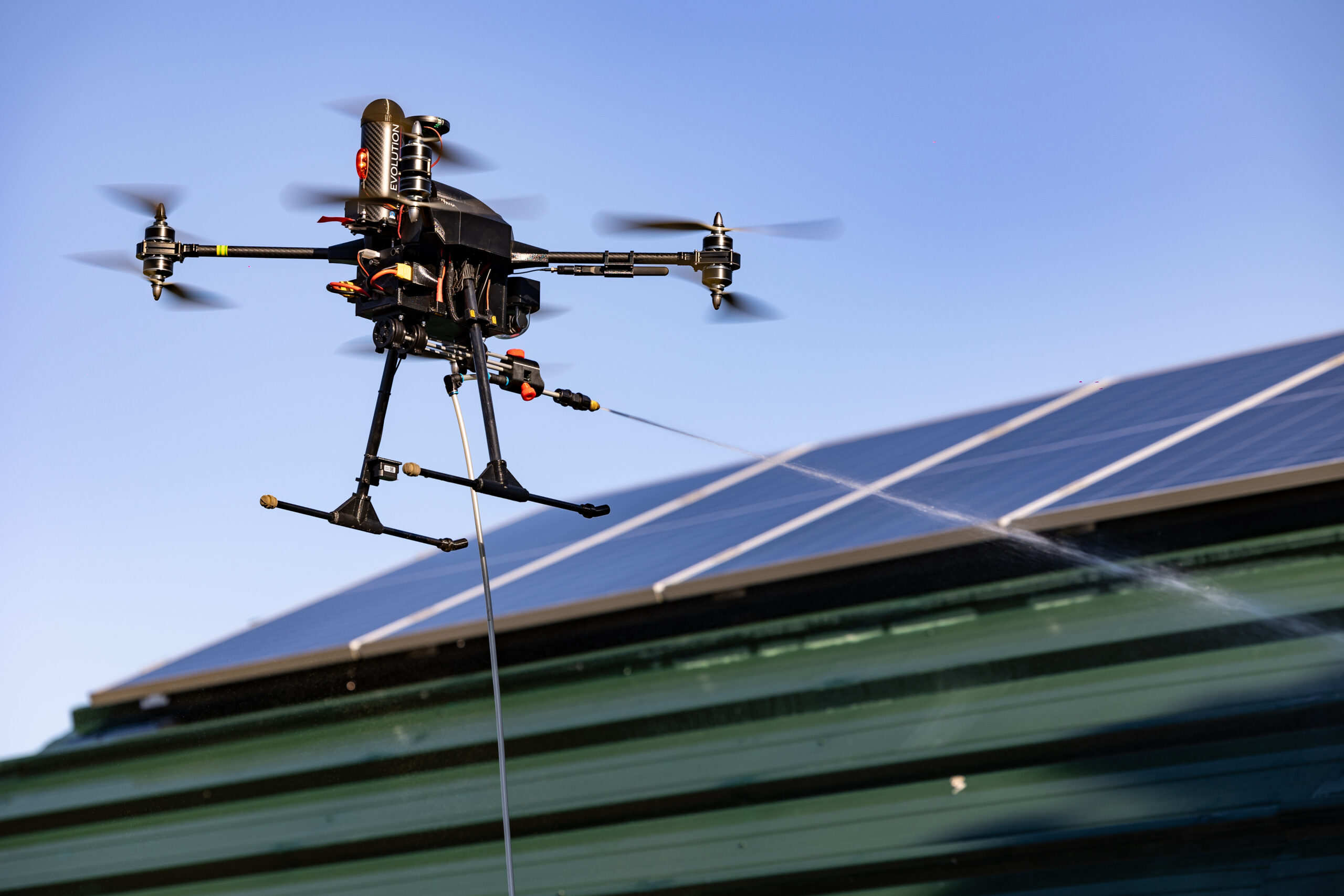 Drone de pulvérisation en vol au-dessus d’une toiture équipée de panneaux solaires